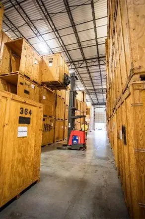 Person operating a forklift with crates around them at the storage warehouse for Good Greek Moving & Storage